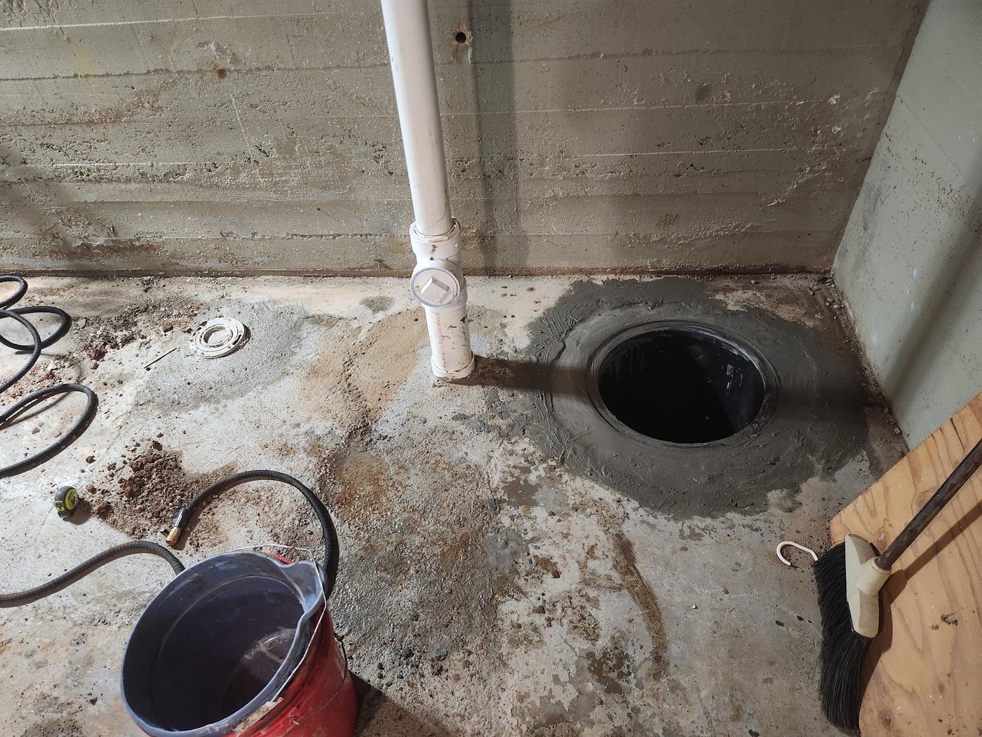 A sump pit cut into a basement slab, part way through.